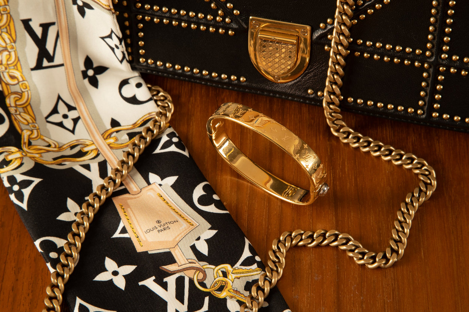 An editorial flatlay of a vintage designer handbag, silk scarf and pearls on linen.