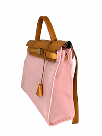 Pre-owned Hermès Herbag Zip 31 in pink canvas, three-quarter side view showing the top handle, shoulder strap and gusset depth, authenticated by MIKUN
