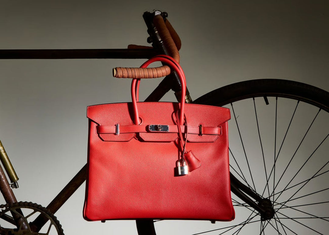 Hands carefully arranging a vintage quilted designer handbag on blush silk.